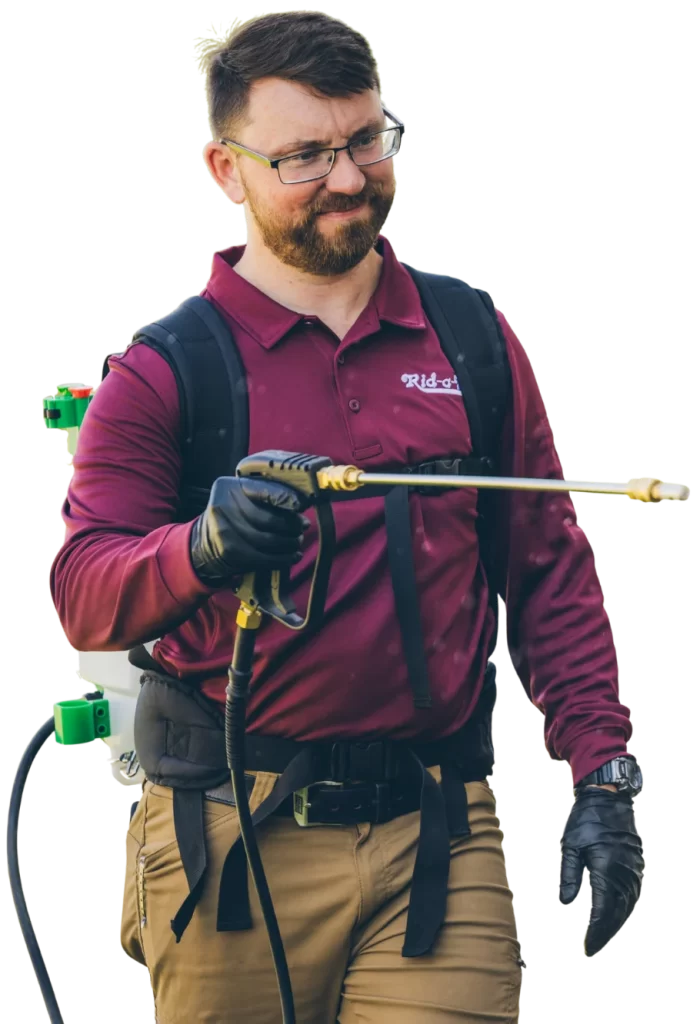 Technician in Rogers AR using eco-friendly pest control spray outdoors